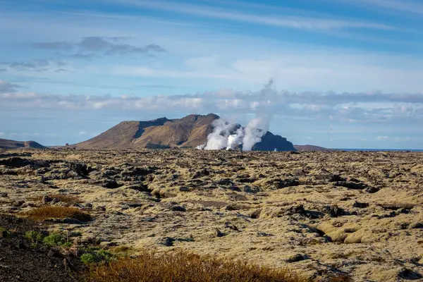 Volcanic landscape of Reykjanes peninsula with lava fields and gas steam of Svartsengi Geothermal Power Plant and Blue Lagoon, seen from road 43, Iceland.