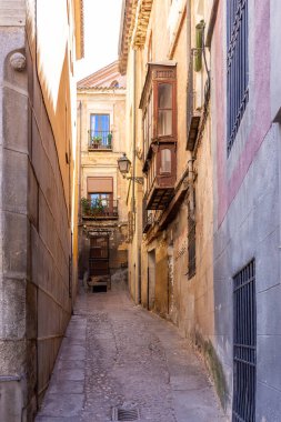 Eski evleri, geleneksel ahşap balkonları ve eski tarz sokak lambaları olan dar İspanyol ortaçağ kaldırımlı caddesi, Toledo, İspanya.