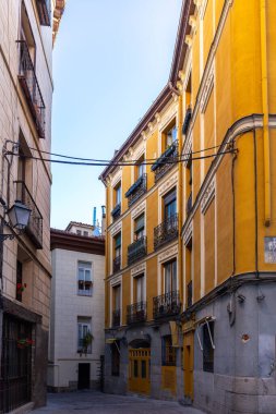 Madrid, İspanya, 09.10.21. Madrid 'deki dar İspanyol ortaçağ kaldırımlı sokak evleri, geleneksel balkonları, eski tarz sokak lambaları ve asılan elektrik kabloları..