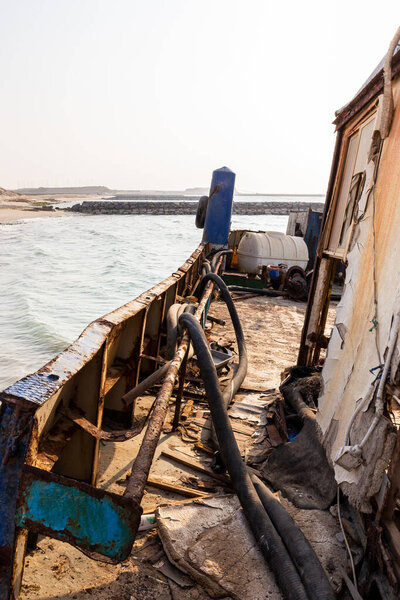 Destroyed and rusty deck of a cargo ship with old bridge, machinery and equipment, washed ashore on the Al Hamriyah beach in Umm Al Quwain, United Arab Emirates.