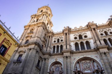 Malaga Katedrali, arka planda lavanta gökyüzü olan aşağıdan görülüyor. Rönesans tarzı ortaçağ Katolik kilisesi kemer ve portallı barok cepheli. Malaga, İspanya.