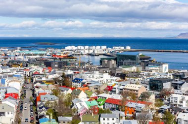 Reykjavik, İzlanda manzarası, renkli evler ve binalar, eski liman, gemiler ve yakıt deposu, güneşli bir günde Hallgrimskirkja kilise kulesinden görünen okyanus manzarası.