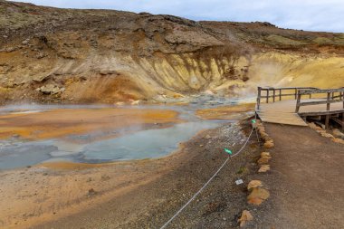Krisuvik 'teki Seltun Jeotermal Bölgesi' nin manzarası. Sıcak su kaynakları, sülfür tepelerinin sarı ve turuncu renkleri ve İzlanda, İzlanda 'daki turist kaldırımları..