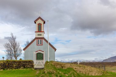 Keldnakirkja Kilisesi, Keldur 'da 1875' ten kalma, İzlanda 'nın mevcut en eski çim çiftliği, arka planda karlı dağlarla kaplı bir manzara..