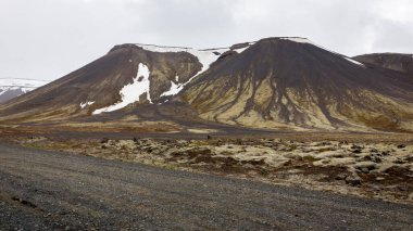 Reykjanes yarımadası. Ham volkanik dağlarla kaplı. Kar, lav tarlaları ve siyah çakıl yolu..