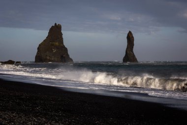 Reynisdrangar bazalt deniz yığınları Reynisfjara Kara Kum Sahili, İzlanda 'da sinsi dalgalar kıyıya çarpıyor..