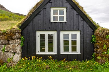 Skogar Açık Hava Müzesi 'ndeki geleneksel çim evi, çatısı yosun ve yosun kaplı siyah ahşap ön cephe bina, beyaz pencere çerçeveleri, İzlanda.