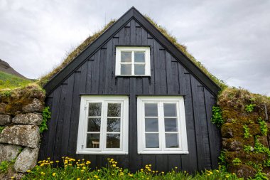 Skogar Açık Hava Müzesi 'ndeki geleneksel çim evi, çatısı yosun ve yosun kaplı siyah ahşap ön cephe bina, beyaz pencere çerçeveleri, İzlanda.