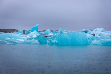 İzlanda 'daki Jokulsarlon buzul gölü. Atlas Okyanusu' nda kayan buzullardan parlak mavi buzdağları var..