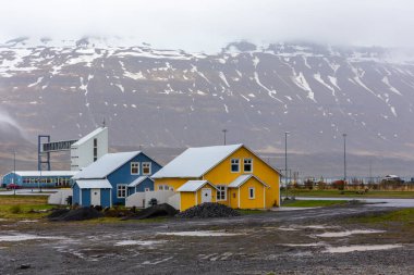 İzlanda 'nın Seydisfjordur kasabasında geleneksel İzlanda renkli konut binaları, karlı dağlar ve arka planda feribot terminali var..