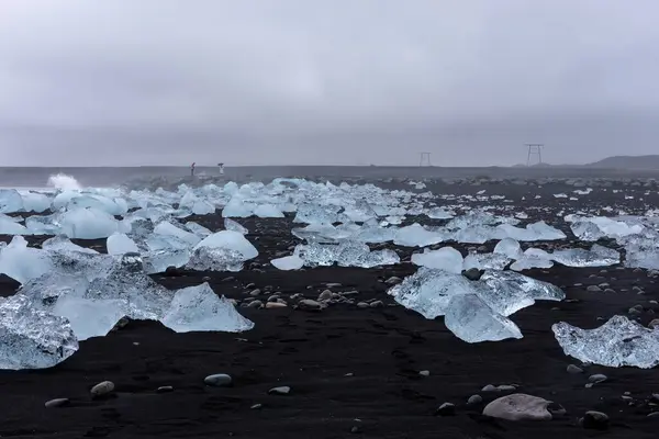 stock image Diamond Beach in Iceland - transparent ice bergs washed ashore  on black sand beach with seascape in the background.