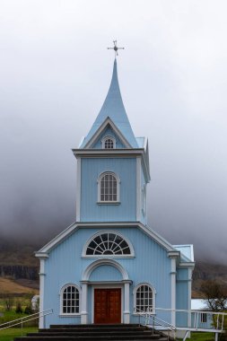 Seydisfjordur 'daki Mavi Kilise (Seydisfjardarkirkja), parlak mavi binanın dış görünüşü, arka planda sisli dağlar, İzlanda.