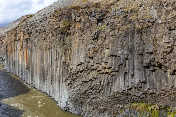 stock image Studlagil Canyon (The Basalt Canyon) view of the ravine with brown glacial river and vertical hexagonal basalt columns, Iceland.