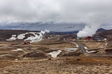 İzlanda 'nın Myvatn volkanik bölgesindeki Krafla jeotermal santrali, kıvrımlı yolu ve arka planda dağları olan manzara manzarası.