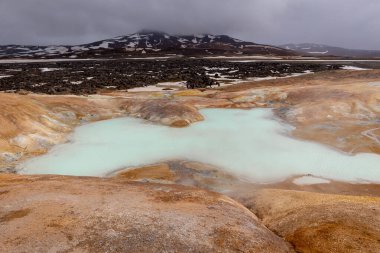 Leirhnjukur 'un volkanik manzarası, İzlanda' nın Myvatn Jeotermal Bölgesi, arkaplanda turkuaz sülfürlü göller, çamur yayları ve dağlar.