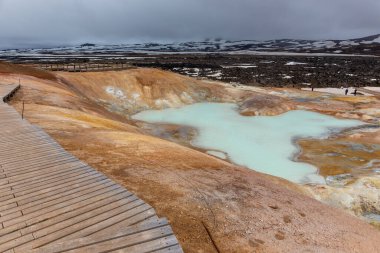 İzlanda Myvatn Jeotermal Bölgesi 'ndeki Leirhnjukur volkanik manzarası turkuaz sülfürlü göller, çamur pınarları, buhar bacaları ve turistler için yürüyen platformlar.