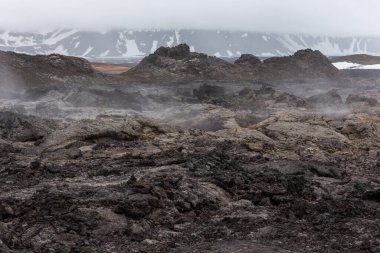 Leirhnjukur volkanik lav tarlaları İzlanda 'nın Myvatn Jeotermal Alanı' nda, donmuş magma ve buharlı bacalarıyla.
