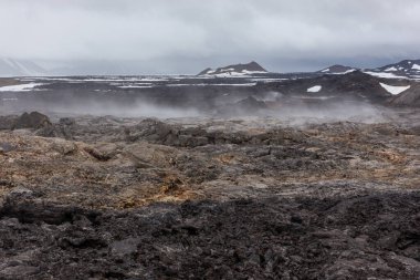 Leirhnjukur volkanik lav tarlaları İzlanda 'nın Myvatn Jeotermal Alanı' nda, donmuş magma ve buharlı bacalarıyla.