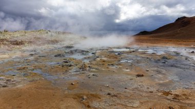 Kuzey İzlanda 'nın Hver, Myvatn Jeotermal Bölgesi' nde kaynamış ve buharlaşmış gri çamur kapları ve turuncu sülfür toprağı..