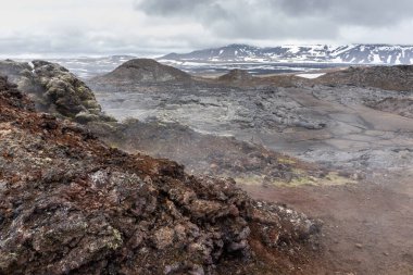 Leirhnjukur volkanik lav tarlaları İzlanda 'nın Myvatn Jeotermal Alanı' nda, donmuş magma ve buharlı bacalarıyla.