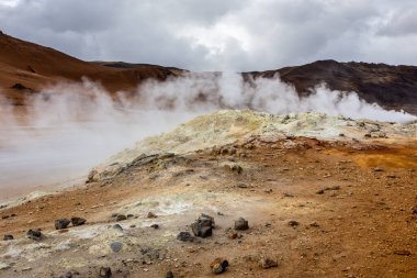 Volcanic landscape of Hverir, Myvatn Geothermal Area in Iceland, with steaming hot springs and orange mineral soil and rocks. clipart