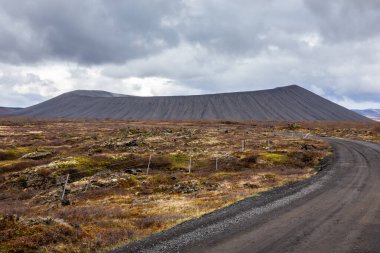 Kuzey İzlanda 'daki Hverfjall volkanik konisi, etrafında lav tarlaları ve siyah toprak yol olan manzara.