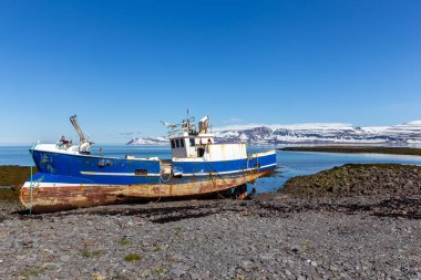 Eski paslı çelik balıkçı teknesi Westfjords, İzlanda kıyılarında karlı dağlarla karlı arka planda karla kaplı..