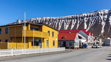 Isafjordur, İzlanda, 23.05.22. Geleneksel İzlanda binaları ve karla kaplı lav kayaları ile Ürdün şehir caddesi.