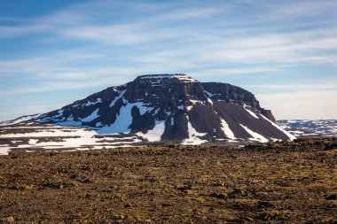 Arnarfjordur, Westfjords, İzlanda 'da volkanik kaya oluşumları ve kayalıklar karla kaplıdır.. 