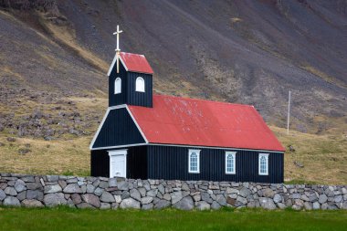 Sauraejarkirkja (Sauraejar Church) with black wooden facade and red roof, next to Raudisandur beach in Westfjords, Iceland. clipart