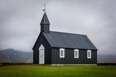 Snaefellsnes yarımadası, İzlanda 'daki Budakirkja Kilisesi (Siyah İzlanda Kilisesi), yeşil çimenler ve bulutlu gökyüzü.