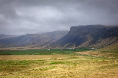 Snaefellsjokull Buzulu ve Snaefellsnes yarımadası çiftlik binaları, volkanik kayalıklar, bulutlu dağ tepeleri ve otlaklar, İzlanda.