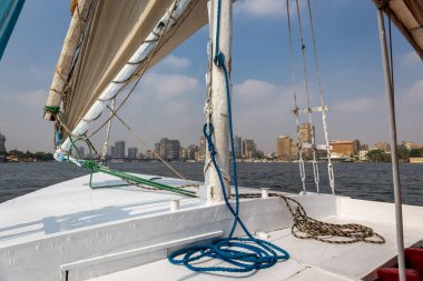 Nil Nehri 'nde geleneksel ahşap yelkenli, doğal pamuk yelkenli, halat ve teçhizatlı güverte manzarası, Nasser' in konut binası ve Nil Nehri çeşmesi olan Giza manzarası..