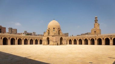 Mısır 'ın Kahire kentindeki İbn Tulun camii, ortasında kubbeli büfe çeşmesi olan avlu manzarası, spiral minare ve etrafındaki sütunlar ve kemerler oyulmuş sıva ile süslenmiş..