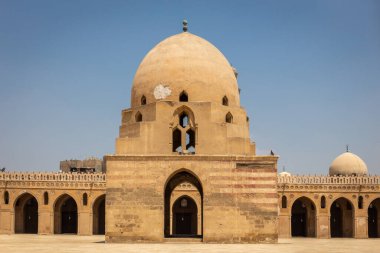 Mısır 'ın Kahire kentindeki İbn Tulun Camii, avlu manzarası ortasında kubbeli büfe çeşmesi ve etrafındaki sütunlar ve kemerler oyulmuş sıva ile süslenmiş..