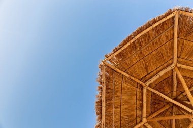 Aşağıdaki köşede sazdan yapılmış plaj şemsiyesi ve mavi gökyüzü, fotokopi alanı, tatiller.