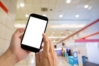 Hand holding mobile phone with blurred image of department store background.