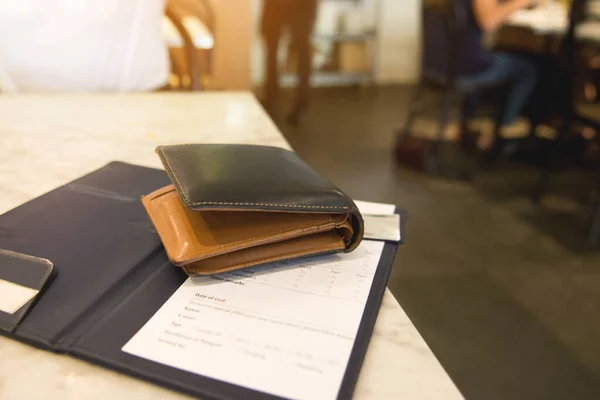 Para ve kredi kartının yumuşak tonu ahşap masada deri bir cüzdanda ve fatura fişi