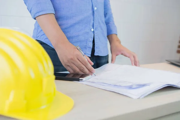 Close up man working of architect sketching a construction project at site construction work with blueprints,engineer inspection in workplace for architectural plan,sketching a construction project ,selective focus ,Business construction concept.