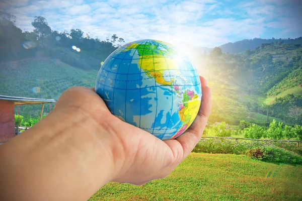 Earth in hands with mountains, sky, nature and sunshine background.