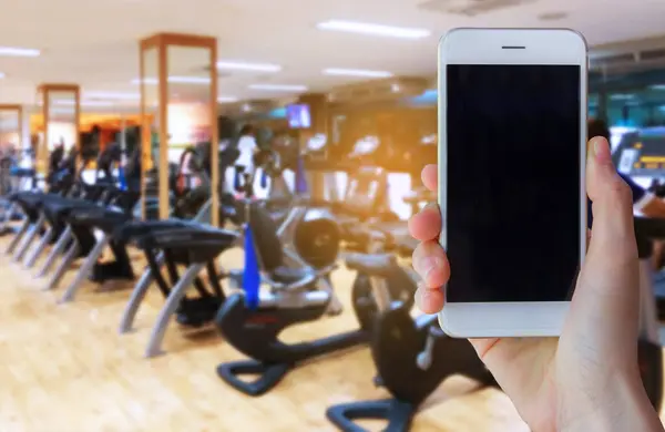 Hand Holding Smartphone Device Sunshine Motion Blur Gym Background — Fotografia de Stock