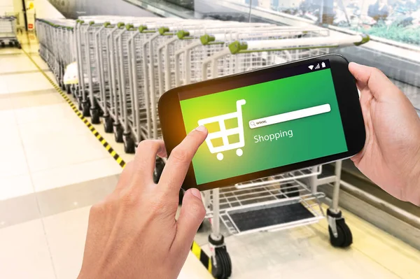 Hand holding mobile phone at supermarket checkout background, e coupon concept