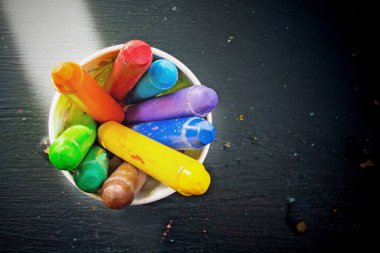 multi color chalk oil pastel in green cup on black background