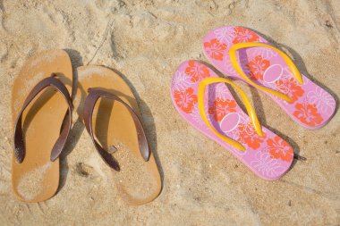 Two flip flops on a sandy ocean beach