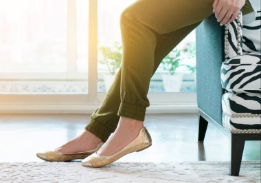 Fashionable beautiful woman and gold casual shoes in the room with sunshine  background.