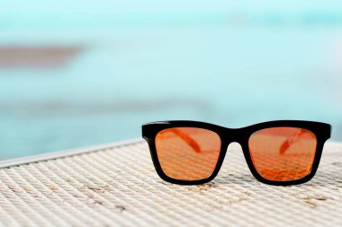 Sunglasses lying on the table with sunshine  beach background.
