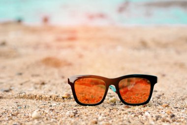 Sunglasses lying on tropical sand beach with sunshine.
