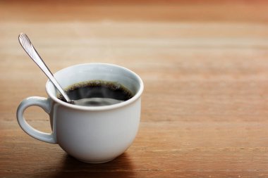 Cups of black coffee with smoke on wood table.