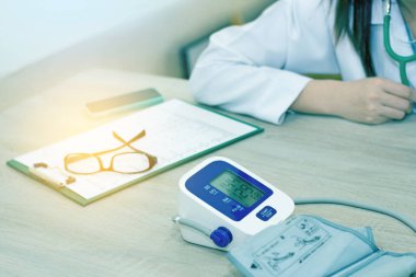 female doctor in office filling out application form with smartphone , sitting at the table in the hospital(bluetone)