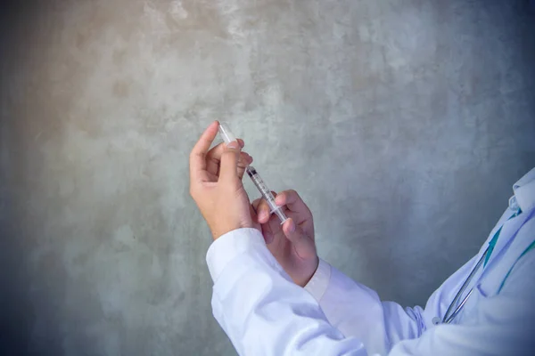 医師は 石の壁の背景にガラス瓶から注射器に薬をダイヤル — ストック写真